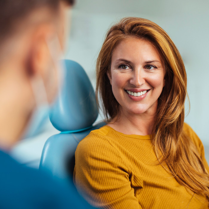 woman smiling while sitting in a chair at the dentist
